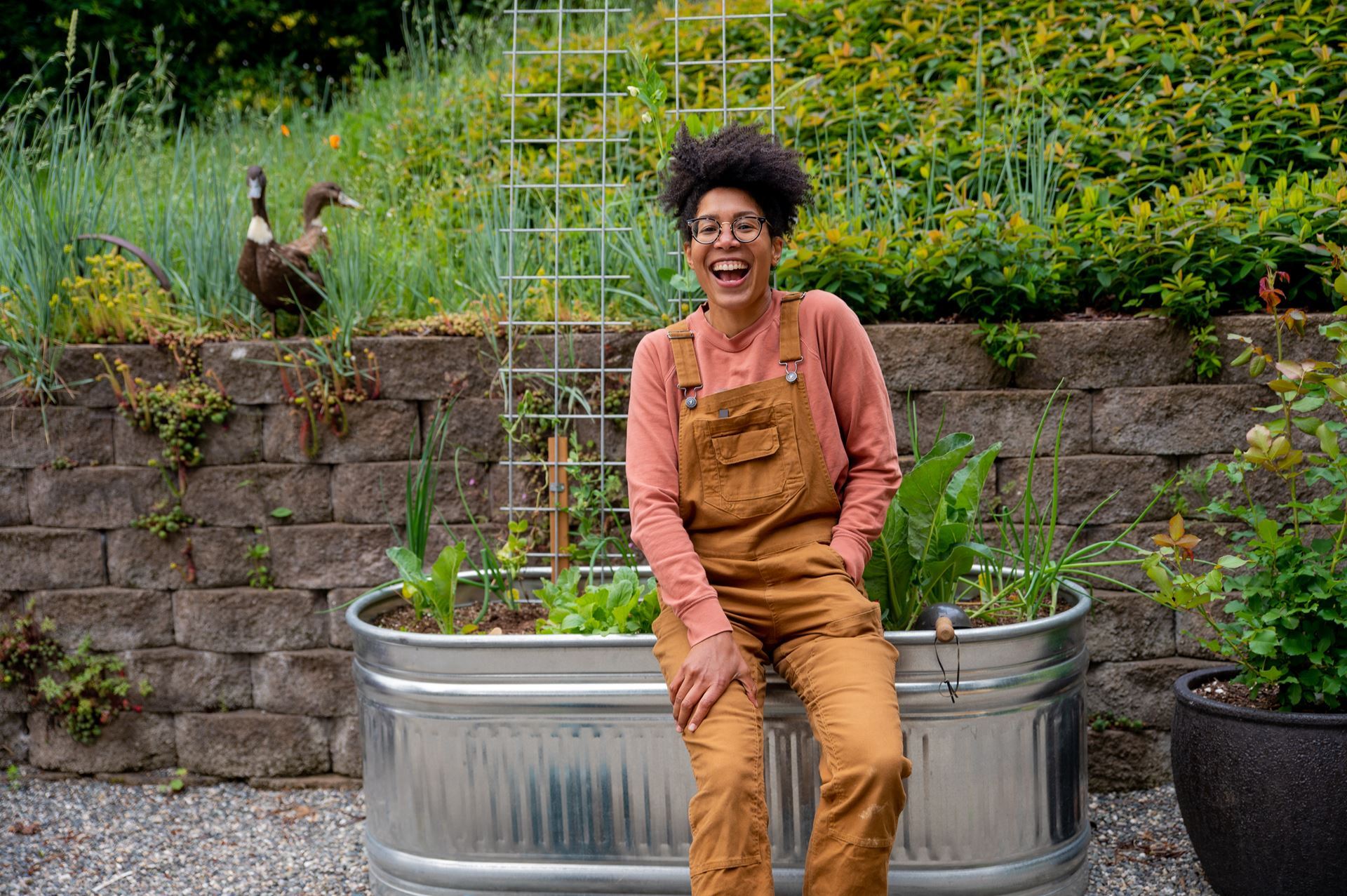 Medium brown-skinned woman sitting on large metal planter